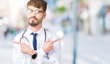 Genç doktor adam giyen hastane kat izole üzerinde arka plan için her iki parmak, farklı yönde ile katılmıyorum işaretleme