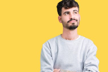 Yakışıklı delikanlı görünümlü yan ve dik dik bakma uzağa düşünce gülümseyen izole arka plan üzerinde Sweatshirt giyiyor.