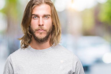 Yüzünde ciddi bir ifade ile izole arka plan üzerinde uzun saçlı Genç yakışıklı adam. Basit ve doğal kameraya bakıyor.