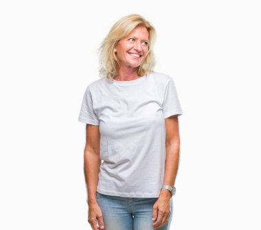 Orta yaş sarışın kadın izole arka plan uzak tarafına gülümseme ile yüzünde, doğal ifade seyir üzerinde. Kendine güvenen gülüyor.