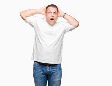 Kafasına, korkmuş ve şaşırmış şok açık ağız ile beyaz t-shirt üzerinde arka plan deli izole ve ile korkuttu orta yaş Arap adam wearig eller