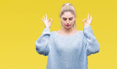 Genç güzel sarışın ve mavi gözlü kadın giyiyor kış kazak izole arka plan üzerinde dinlenmek ve gülümseyen gözlerle kapalı parmak jestle meditasyon yapıyor. Yoga kavramı.