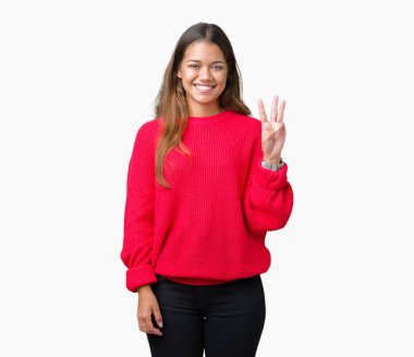 Gösterilen ve parmakları ile işaret izole arka plan üzerinde kırmızı kış kazak giyen genç güzel esmer kadın kendinden emin ve mutlu gülümseyerek iken üçüncü.