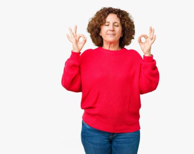 Güzel orta ager üst düzey kadın kırmızı kış kazak izole arka plan üzerinde dinlenmek ve gülümseyen gözlerle kapalı parmak jestle meditasyon yapıyor. Yoga kavramı.