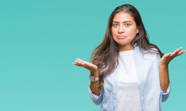 Genç güzel Arap kadın izole arka plan clueless ve şaşkın bir ifadeyle kollar ve eller kaldırdı. Şüphe kavramı.