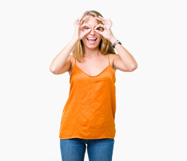 舌を出して指を通して見る目をこだわりの双眼鏡のような ジェスチャーを行う分離の背景にオレンジ色のシャツを着て美しい若い女性 クレイジー式 — ストック写真