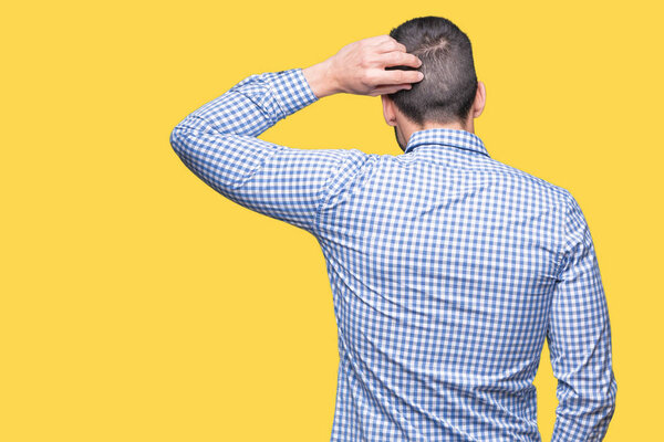 Молодой бизнесмен в очках на изолированном фоне задом наперед думает о сомнениях с поднятой головой
