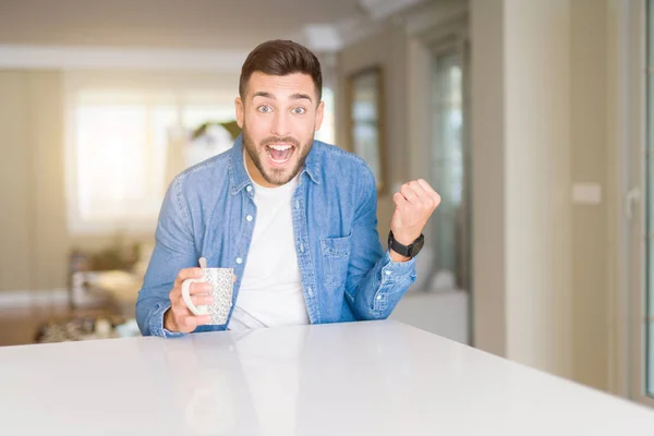 Jovem Homem Bonito Bebendo Uma Xícara Café Casa Gritando Orgulhoso — Fotografia de Stock