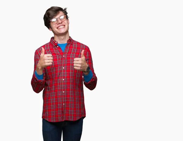 年轻的帅哥戴着眼镜在孤立的背景成功标志做积极的手势用手 竖起大拇指微笑和快乐 带着欢快的表情 获胜者的手势看着镜头 — 图库照片