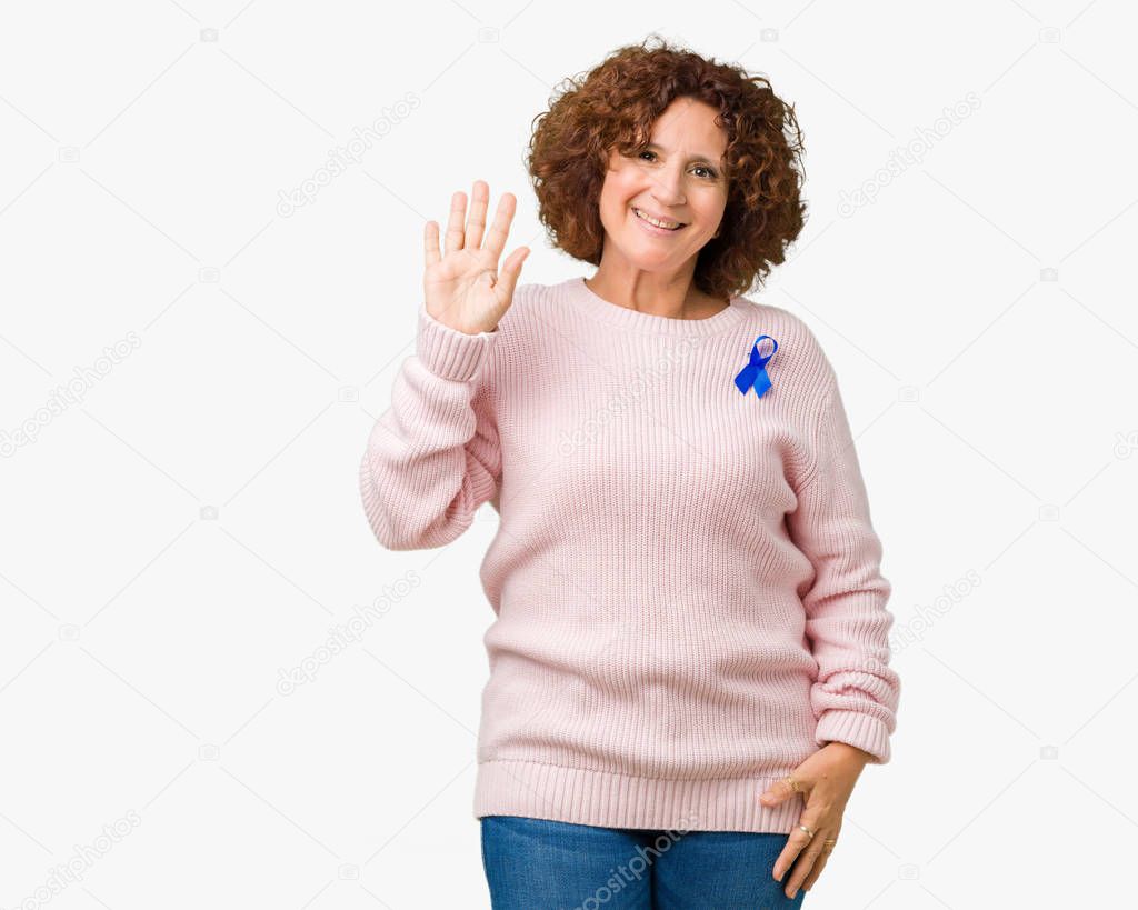 Middle ager senior woman wearing changeable blue color ribbon awareness over isolated background Waiving saying hello happy and smiling, friendly welcome gesture