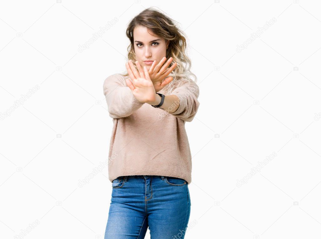 Beautiful young blonde woman wearing sweatershirt over isolated background Rejection expression crossing arms and palms doing negative sign, angry face
