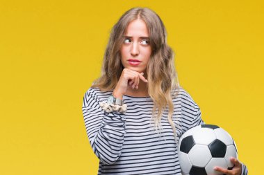 İzole arka plan ciddi bir yüz düşünme hakkında soru, çok karışık bir fikir üzerinde futbol futbol topu tutan genç güzel sarışın kadın