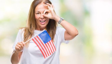Amerika Birleşik Devletleri bayrağı ile mutlu yüz el parmaklarının arasından seyir göz üzerinde ok işaretiyle yapıyor gülümseyen izole arka plan üzerinde tutan orta yaş İspanyol kadın