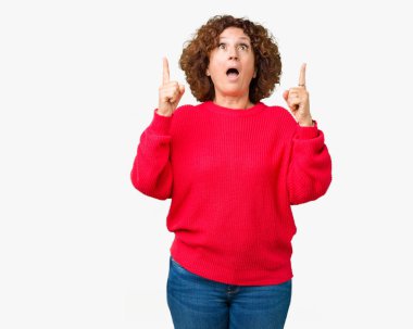 Güzel orta ager üst düzey kadın kırmızı kış kazak üzerinden hayran ve yukarıya bakıyor ve parmakları ile işaret ve silah kaldırdı sürpriz arka plan izole.