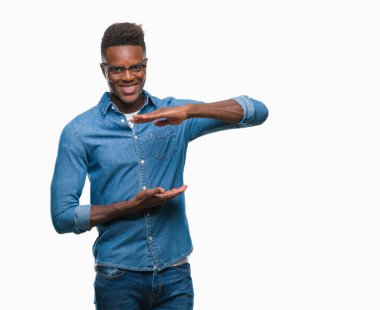 Afrikalı-Amerikalı genç izole arka plan ile büyük ve büyük boy işaret, ölçü birimi sembol gösteren el eller üzerinde. Kameraya bakarak gülümsüyordu. Ölçüm kavramı.
