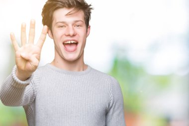 Gösterilen arka plan üzerinde kış kazak giyen genç yakışıklı adam izole ve parmakları ile işaret kendinden emin ve mutlu gülümseyerek süre dört numara.