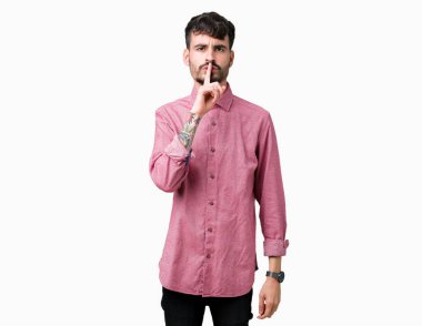 Dudaklarında parmak ile sessiz olmanı izole arka plan üzerinde pembe gömlek giymiş yakışıklı delikanlı. Sessizlik ve gizli kavramı.