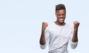 Gülümseyen ve başarı için çığlık genç Afro-Amerikan adam izole arka plan çok mutlu ve heyecanlı kaldırdı, silah ile kazanan jest yapıyor. Kutlama kavramı.