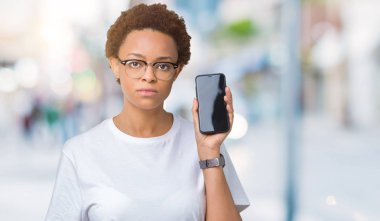 Genç Afro-Amerikan kadın gösteren smartphone ekran acımak yüz ciddi düşünüyorum üstünde kendine güvenen bir ifade ile izole arka plan üzerinde