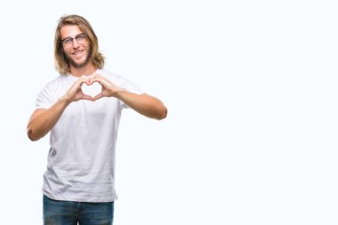 Yakışıklı delikanlı aşık kalp simgesi ve elleriyle şekil gösteren gülümseyen izole arka plan üzerinde gözlük takan uzun saçlı. Romantik kavramı.