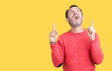 İzole arka plan üzerinde kış kazak giymiş yakışıklı orta yaş ağarmış komuta sizde hayran ve yukarıya bakıp parmakları ile işaret şaşırttı ve silah kaldırdı.