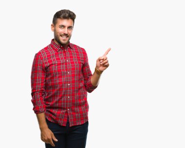 Kameraya bakarak yan el ve parmak ile işaret eden genç yakışıklı adam yüzünde kocaman bir gülümseme ile izole arka plan üzerinde.