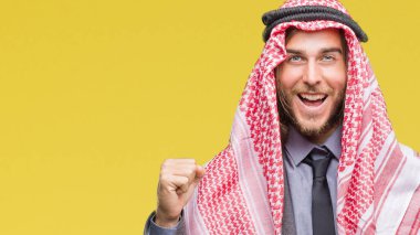 Genç yakışıklı Arap adam uzun saçlı keffiyeh izole arka plan kutlama üzerinde giyen şaşırttı ve başarı için kaldırdı kollarını açarak hayret ve gözleri açık. Kazanan kavramı.