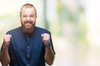 Genç beyaz hipster adam izole arka kolları olan başarı için heyecan üzerinde zafer kutluyor gülümseyen kaldırdı. Kazanan kavramı.