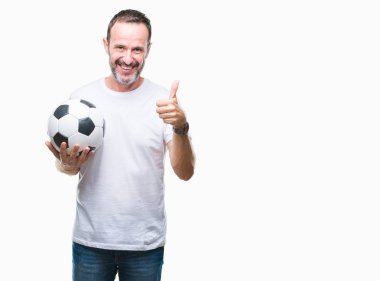 Orta yaş ağarmış komuta sizde izole arka plan üzerinde futbol futbol topu ok işareti, başparmak ile parmak, mükemmel işareti yapıyor kocaman bir gülümseme ile mutlu holding