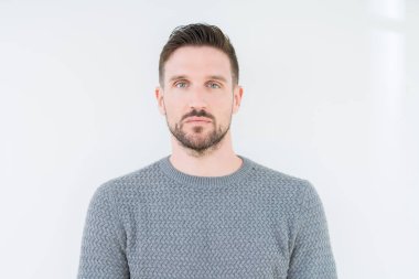 Yüzünde ciddi bir ifade ile izole arka plan üzerinde rahat kazak giyen genç yakışıklı adam. Basit ve doğal kameraya bakıyor.