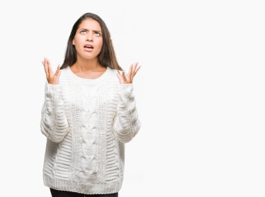 Üzerinde kış kazak giyen genç güzel Arap kadın arka plan deli izole ve deli bağırarak ve agresif ifade ve silah kaldırdı bağırıyor. Hayal kırıklığı kavramı.