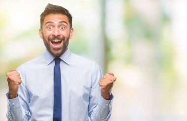 Yetişkin İspanyol iş adamı izole arka plan kutlama üzerinde şaşırttı ve başarı için kaldırdı kollarını açarak hayret ve gözleri açık. Kazanan kavramı.