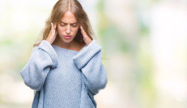 Üzerinde kış kazak giyen güzel genç sarışın kadın izole arka plan baş baş ağrısı için el ile çünkü stres. Migren muzdarip.