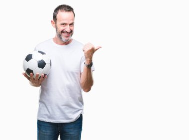 Orta yaş ağarmış komuta sizde işaret ve başparmak kadar mutlu yüz gülümseyen tarafı ile gösteren izole arka plan üzerinde futbol futbol topu tutan