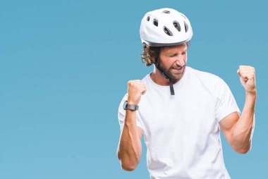 Üzerinde güvenlik kask giymiş yakışıklı İspanyol bisikletçi adam arka plan çok mutlu ve heyecanlı kaldırdı, silah ile kazanan jest yapıyor gülümseyen ve başarı için çığlık izole. Kutlama kavramı.