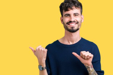 Yakışıklı delikanlı izole arka plan üzerinde emin gülümseyen arkasından el ve kadar başparmak ile işaret