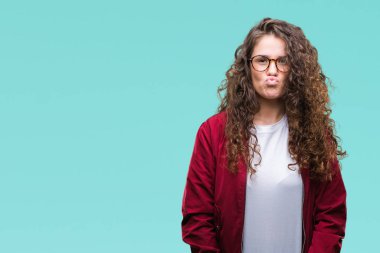 Güzel esmer kıvırcık saçlı Genç kız komik surat ile yanakları şişirme izole arka plan üzerinde ceket ve gözlük takıyor. Ağız ile hava, deli ifade şişirilmiş.