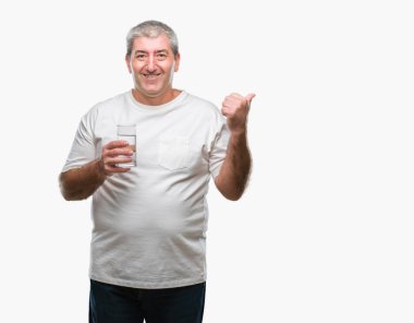 Üst düzey yakışıklı işaret ve başparmak kadar mutlu yüz gülümseyen tarafı ile gösteren izole arka plan üzerinde bardak su içme