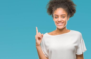 Genç afro Amerikalı kadın ve kendinden emin ve mutlu gülümseyerek süre parmak numaralı yukarıyı gösteren izole arka plan üzerinde.