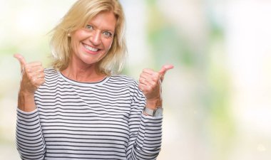 Orta yaş sarışın kadın el ile pozitif jest yapıyor izole arka plan başarı işareti yüzünden başparmak gülümseyen ve mutlu. Neşeli bir ifadeyle, kazanan jest kameraya bakıyor.