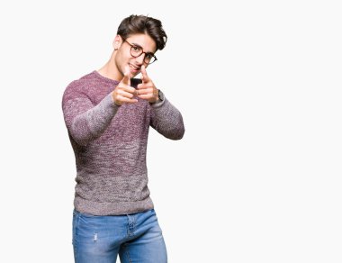 Fotoğraf makinesi ile mutlu ve komik yüz için parmakları işaret izole arka plan üzerinde gözlük takan yakışıklı delikanlı. İyi enerji ve vibes.