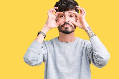 Parmaklarıyla, Uykulu ve sabah yorgunluk için yorgun gözlerini açmaya çalışırken izole arka plan üzerinde sweatshirt giyen genç yakışıklı adam