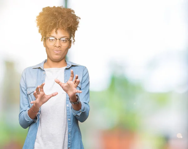 Beautiful young african american woman wearing glasses over isolated background disgusted expression, displeased and fearful doing disgust face because aversion reaction. With hands raised. Annoying concept.