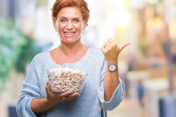 Korzystna Starszy Rude Kaukaski Kobieta Jedzenie Popcorn Białym Tle Wskazując — Zdjęcie stockowe
