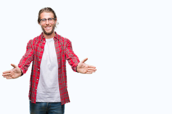 Young handsome man with long hair wearing glasses over isolated background looking at the camera smiling with open arms for hug. Cheerful expression embracing happiness.