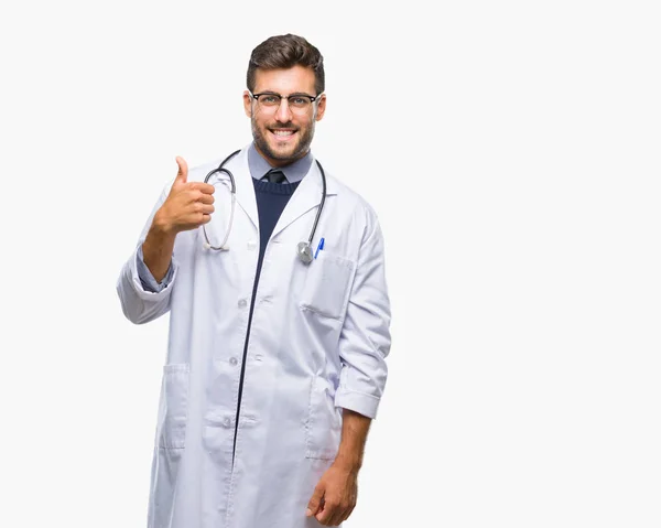 年轻英俊的医生在孤立的背景下做快乐大拇指手势与手 批准表达式看相机与显示成功 — 图库照片