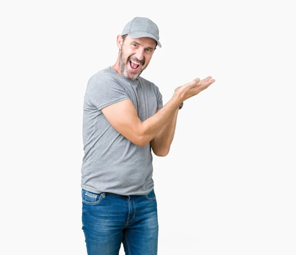 ハンサムな中年白髪年配の男性のスポーツ帽をかぶって分離背景手とひら 広告笑顔幸せと自信を持って提示側を指しています — ストック写真