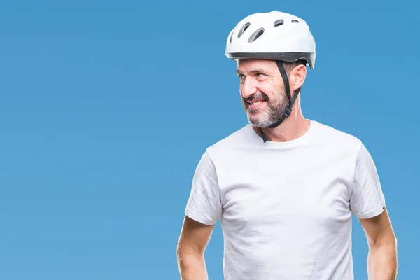 Middle age senior hoary cyclist man wearing bike safety helment isolated background looking away to side with smile on face, natural expression. Laughing confident.