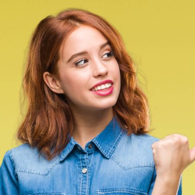 Seyir ve başparmak yanında yukarıyı mutlu yüz ile gülümseyen izole arka plan üzerinde genç güzel kadın.