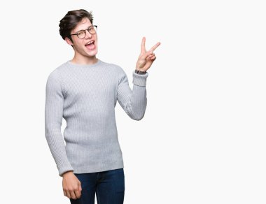 Mutlu yüz zafer işareti yaparken kameraya göz kırpıyor ile gülümseyen izole arka plan üzerinde gözlük takan yakışıklı delikanlı. İki numaralı.